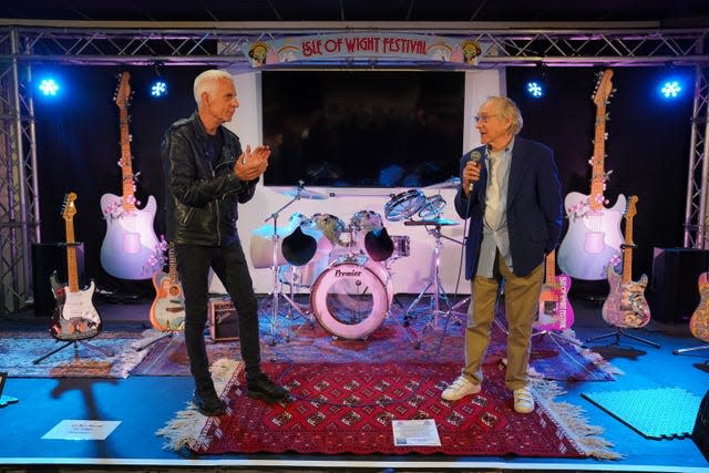 Two men standing in front of a drum kit 