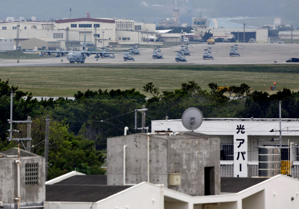 FILE - A military plane and helicopters are seen at Marine Corps Air Station Futenma behind a residential area in Ginowan, Okinawa prefecture, Japan, on Dec. 17, 2009. Okinawa on Sunday, May 15, 2022, marks the 50th anniversary of its return to Japan on May 15, 1972, which ended 27 years of U.S. rule after one of the bloodiest battles of World War II was fought on the southern Japanese island. (AP Photo/Shizuo Kambayashi, File)