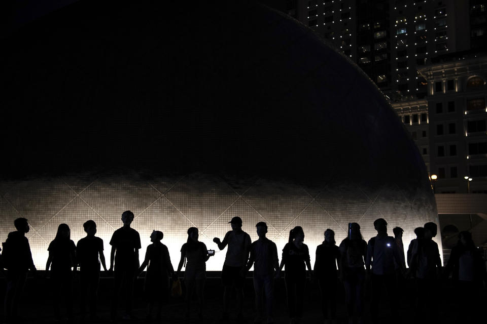 Protesters wear mask and link their hands forming a human chain during a protest in Hong Kong, Friday, Oct. 18, 2019. Hong Kong pro-democracy protesters are donning cartoon/superheroes masks as they formed a human chain across the semiautonomous Chinese city, in defiance of a government ban on face coverings. (AP Photo/Felipe Dana)