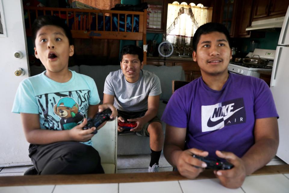 Julio Flores, center, plays video games with his brothers Angel, left, and David