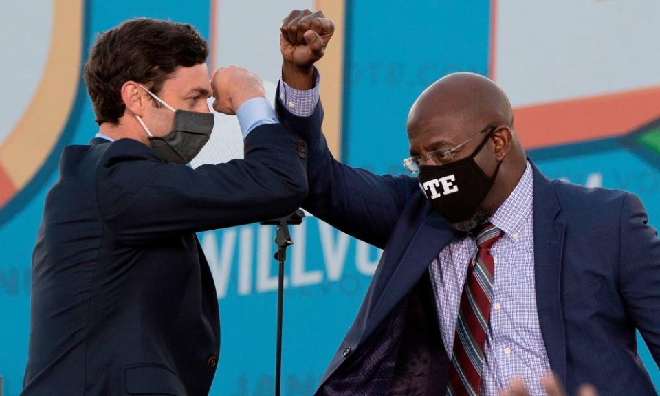 Jon Ossoff and the Rev Raphael Warnock bump elbows on stage during a rally with Joe Biden in Atlanta, Georgia, on 4 January.