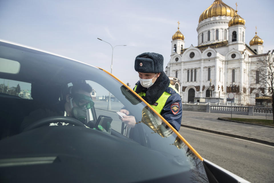 A Russian traffic police officer checks documents of a driver to ensure a self-isolation regime due to coronavirus, with the Christ the Savior Cathedral in the background, in Moscow, Russia, Monday, April 13, 2020. The new coronavirus causes mild or moderate symptoms for most people, but for some, especially older adults and people with existing health problems, it can cause more severe illness or death. (AP Photo/Pavel Golovkin)