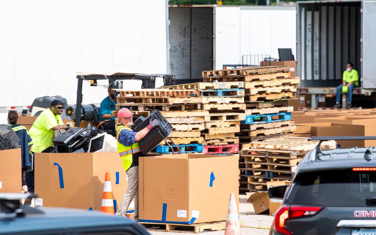 Employees of Cook Inc. and Big Boy Moving Services load discarded electronics into large cardboard bins June 26, 2021, during the Community Electronic Recycling Day at the Cook Profile Park facility.