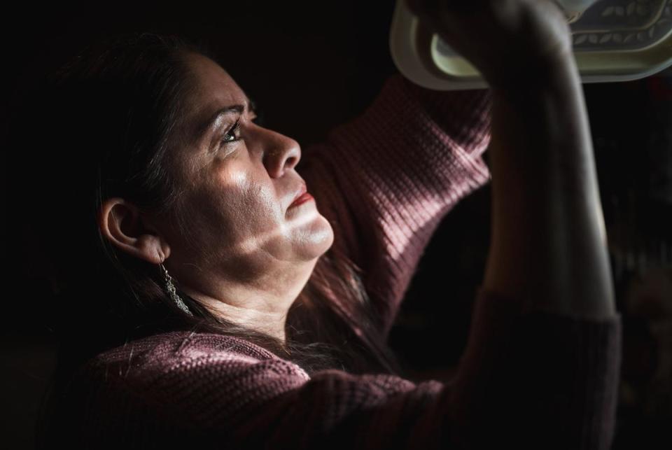 Juvencia Padilla reaches for dishes while preparing dinner for her family. She raises her two sons by herself while being a caregiver to her son, Tino, who is paralyzed from the waist down.  Fort Hancock, Texas. November 28, 2023.