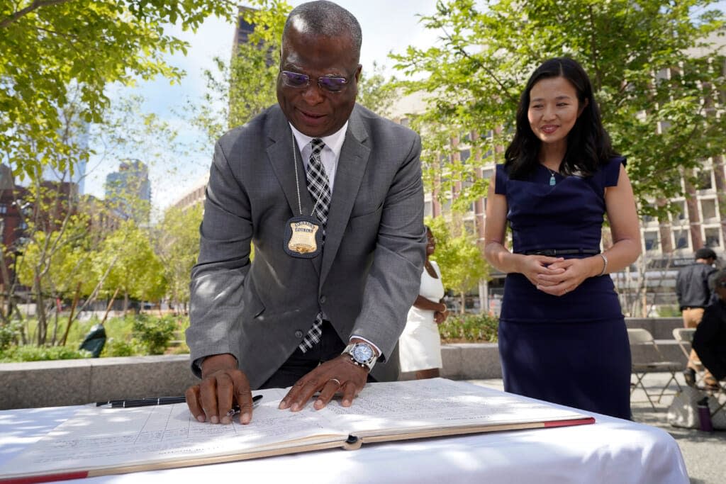 Newly sworn in Boston Police Commissioner Michael Cox, left, signs the City of Boston qualifications book, also known as the “oath book,” as Mayor Michelle Wu, right, looks on during swearing-in ceremonies, Monday, Aug. 15, 2022, in Boston. (AP Photo/Steven Senne)