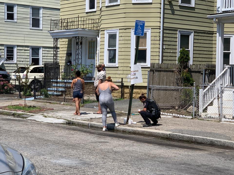 A Providence police officer removed price tags from a candle at the site of a makeshift memorial for a 15-year-old boy found shot to death in a driveway on Wallace Street.