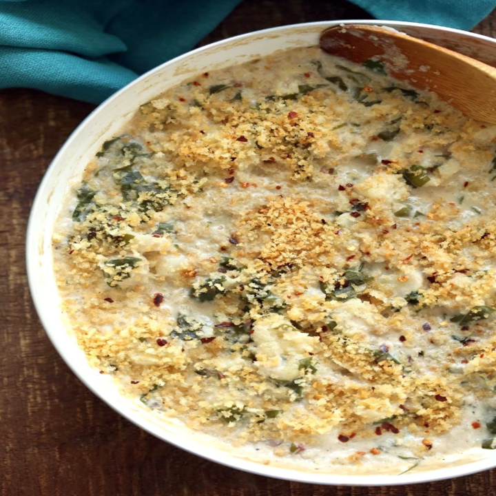 A skillet with spinach, crumbs, cheese, and cauliflower