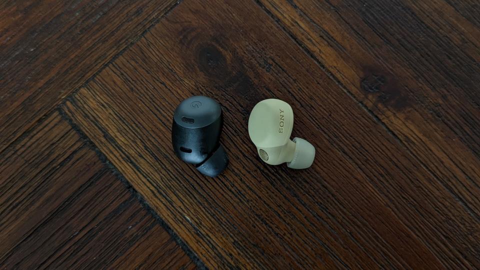 A black Google Pixel Buds Pro right earbud next to a beige Sony LinkBuds S right earbud on a wooden table. (Photo: Yahoo Lifestyle Singapore)