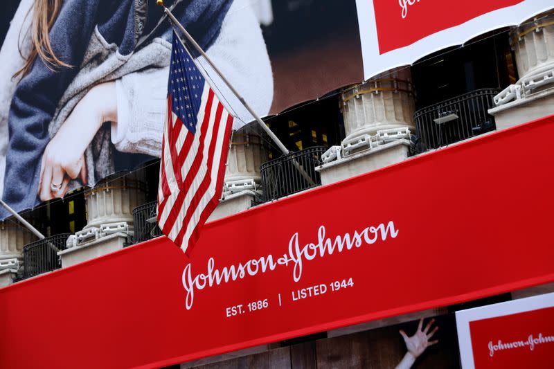 FILE PHOTO: The U.S. flag is seen over the company logo for Johnson & Johnson to celebrate the 75th anniversary of the company's listing at the NYSE in New York