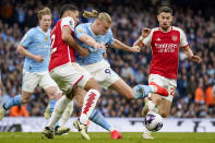 Manchester City's Erling Haaland, center right, duels for the ball with Arsenal's William Saliba during the English Premier League soccer match between Manchester City and Arsenal at the Etihad stadium in Manchester, England, Sunday, March 31, 2024. (AP Photo/Dave Thompson)