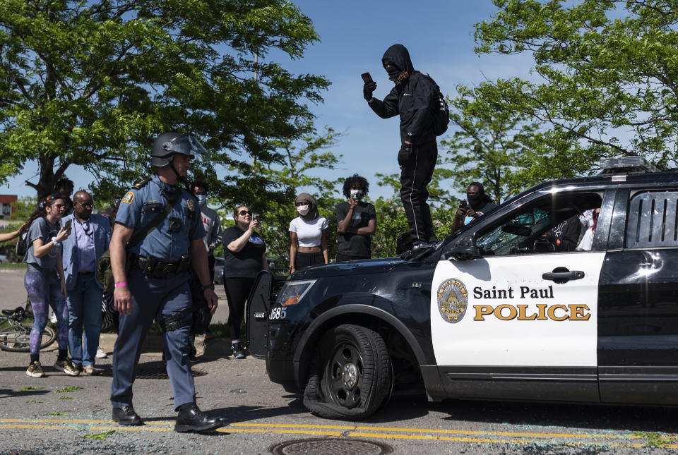 A protester confronts a police officer while standing on a destroyed cruiser in St. Paul on May 28. | Stephen Maturen—Getty Images