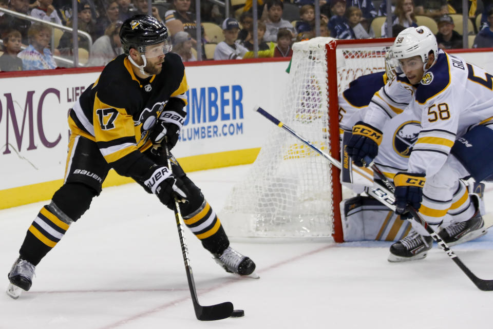 Pittsburgh Penguins' Bryan Rust (17) brings the puck around the net as Buffalo Sabres' John Gilmour (58) defends right before Rust snapped a shot and scored during the second period of an NHL preseason hockey game, Saturday, Sept. 28, 2019, in Pittsburgh. (AP Photo/Keith Srakocic)