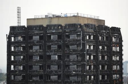 Workers stand on the roof of the burnt out remains of the Grenfell tower in London, Britain, October 16, 2017. REUTERS/Hannah Mckay