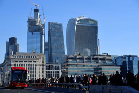 FILE PHOTO: Workers are seen crossing London Bridge with City of London skyscrapers seen behind during the morning rush hour in London, Britain, September 25, 2018. REUTERS/Toby Melville/File Photo