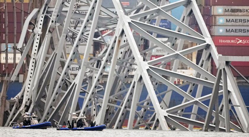 Police dive boats work around a cargo ship that is stuck under the part of the structure of the Francis Scott Key Bridge after the ship hit the bridge Wednesday, March 27, 2024, in Baltimore, Md. (AP Photo/Steve Helber)