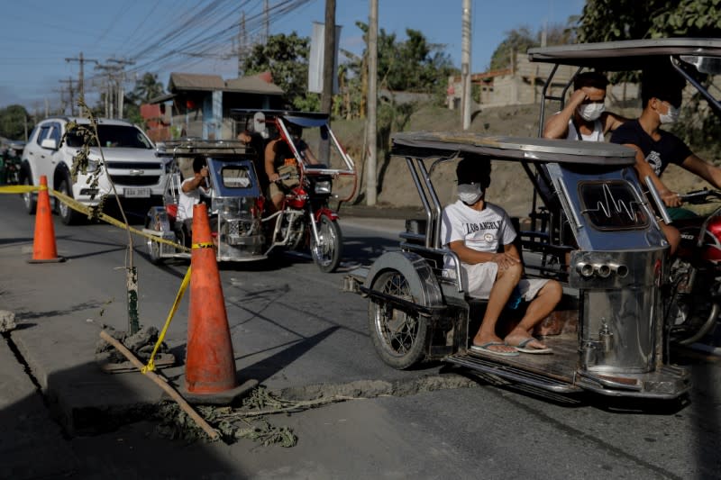 Vehicles ride past a fissure from the aftermath of Taal Volcano's eruption in Lemery