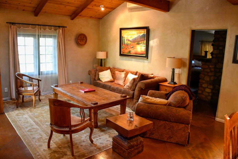 The inside of a hotel suite with a couch, chairs and tables.