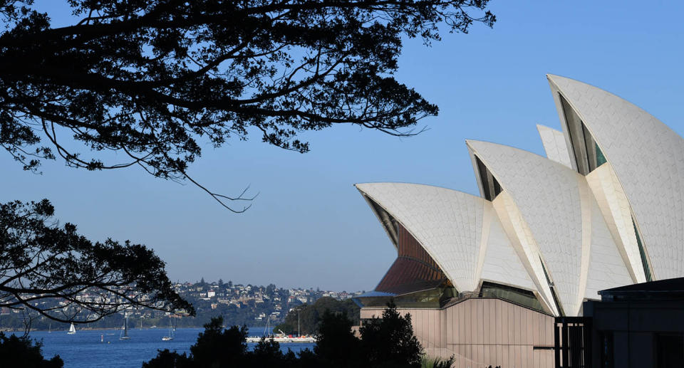 To the left of the image is the side of the Sydney Opera House on a sunny day.