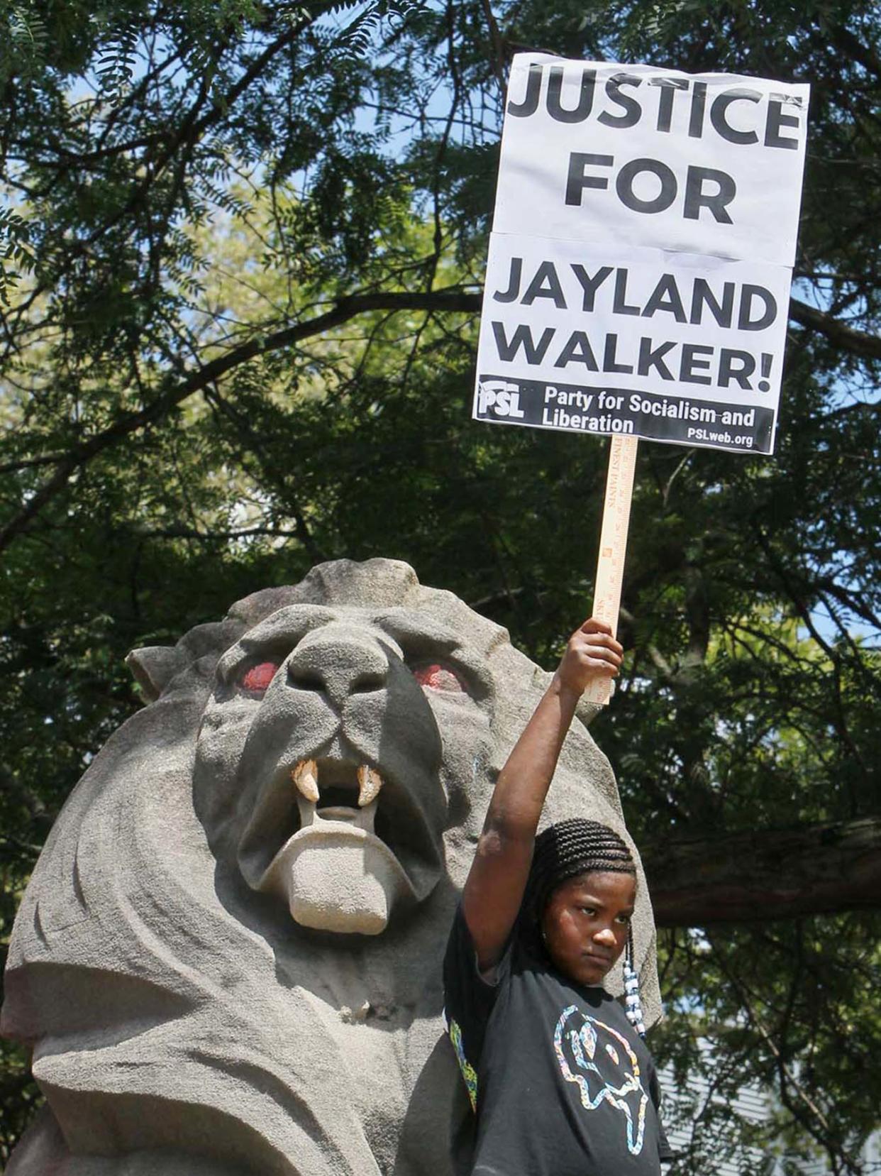 A young activist holds a sign in front of one of the lions at the Summit County Courthouse during a protest of the police shooting of Jayland Walker organized by the Party for Socialism and Liberation on July 9, 2022, in Akron.
