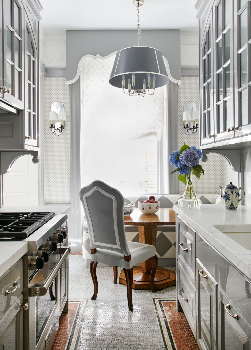 in the kitchen the original mosaic tile floors endure their scale repeated in a fleur de lis wallpaper in the dining area the banquette is upholstered in 1940s glam diamond patterned leathers and the table is a biedermeier reproduction commissioned by baratta while the profile of the window pelmet is pure theater