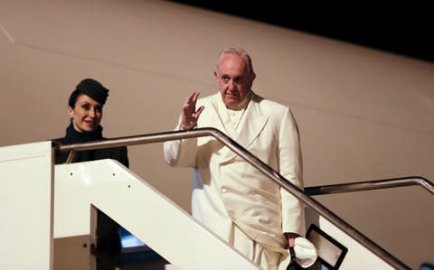 Pope Francis waves to journalists as he boards the plane for his six-day trip to Myanmar and Bangladesh, at Rome's Leonardo da Vinci international airport - Credit: AP