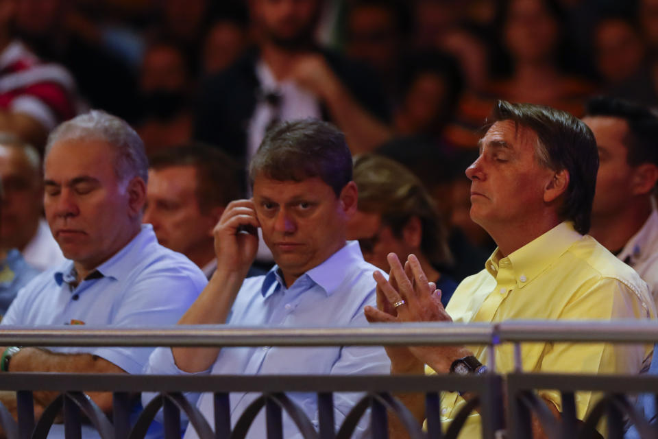 Brazil's President Jair Bolsonaro, right, who running for reelection, Sao Paulo candidate for governor Tarcisio de Freitas, center, and Brazil's health minister Marcelo Queiroga, left, attend in a Mass at the National Sanctuary of Our Lady Aparecida on her feast day in Aparecida, Sao Paulo state, Brazil, Wednesday, Oct. 12, 2022. Bolsonaro will face Luiz Inacio "Lula" da Silva in a presidential runoff on Oct. 30. (AP Photo/Marcelo Chello)