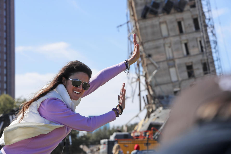 Megan Dority poses for a photo with the so called "Leaning Tower of Dallas" as a crew works to topple the structure north of downtown Dallas, Monday, Feb. 24, 2020. The still standing structure is part of an 11-story building that found a second life online after surviving a first demolition attempt. The former Affiliated Computer Services building inspired jokes and comparisons to Italy's Leaning Tower of Pisa when a Feb. 16 implosion failed to bring down its core. The company that engineered the blast said some explosives did not go off. (AP Photo/LM Otero)