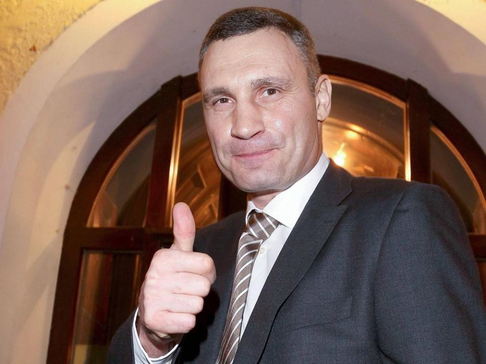 Vitali Klitschko trägt Anzug und Krawatte und posiert mit 