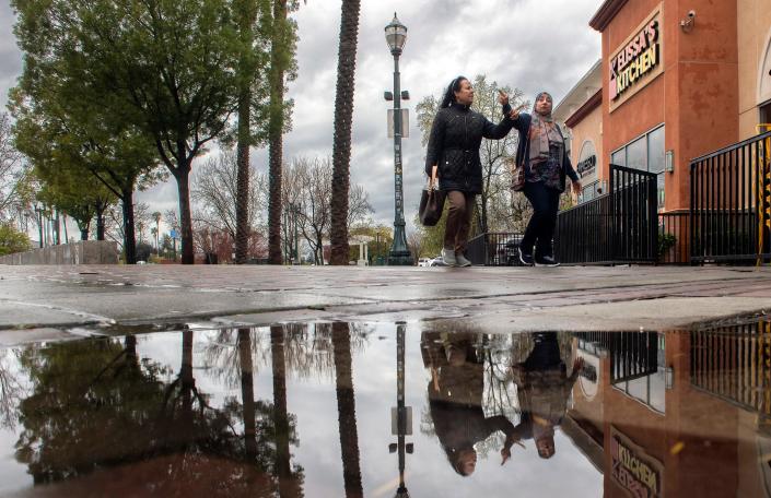 A puddle left by the latest storm reflects the scene around Janet Leigh Plaza in downtown Stockton on Tuesday, Mar. 21. 2023.