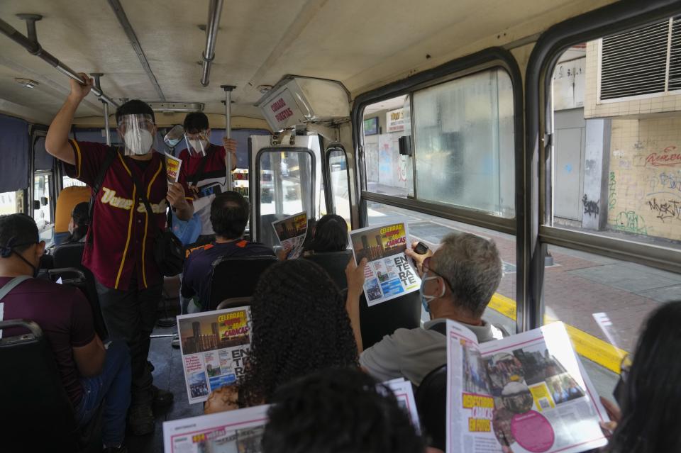 Juan Pablo Lares, left, talks to bus passengers as he and his associate Maximiliano Bruzual deliver their newscast "El Bus TV Capitolio" and hand out free copies of the newspaper "Enterate," in Caracas, Venezuela, Saturday, July 31, 2021. Two decades of governments that see the press as an enemy have pushed Venezuelan journalists to find alternative ways to keep citizens informed. (AP Photo/Ariana Cubillos)