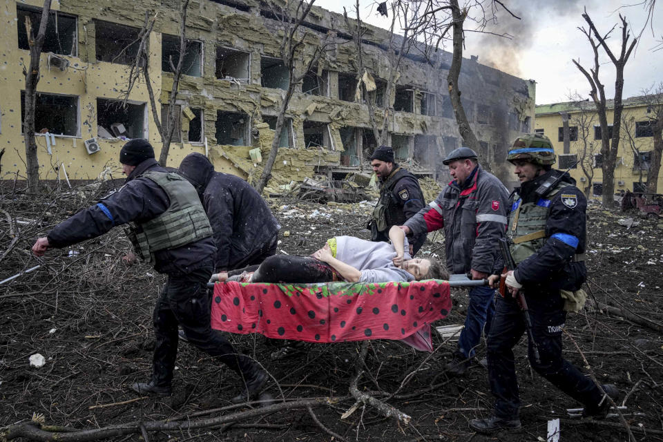 Ukrainian emergency employees and volunteers carry an injured pregnant woman from a maternity hospital damaged by shelling in Mariupol on March 9, 2022. (Evgeniy Maloletka / AP)