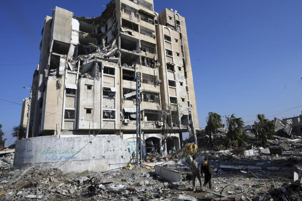 Palestinians walk through destruction from the Israeli bombardment in the Nusseirat refugee camp in Gaza Strip, Friday, Jan. 19, 2024. (AP Photo/Adel Hana)