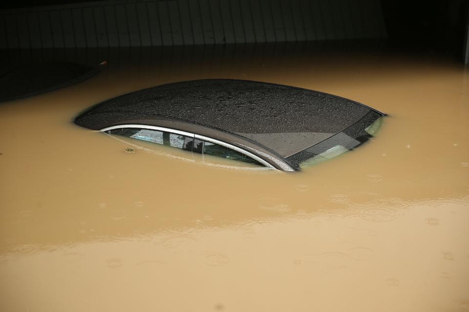 A car, submerged up to the roof in water, is parked in front of a flooded garage in Duesseldorf, Germany, Wednesday morning, July 14, 2021. Storms caused widespread flooding across central Germany overnight, with authorities warning that more rain is on the way.