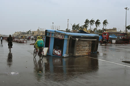 People move past a damaged vehicle after Cyclone Fani hit Puri, in the eastern state of Odisha, India, May 3, 2019. REUTERS/Stringer