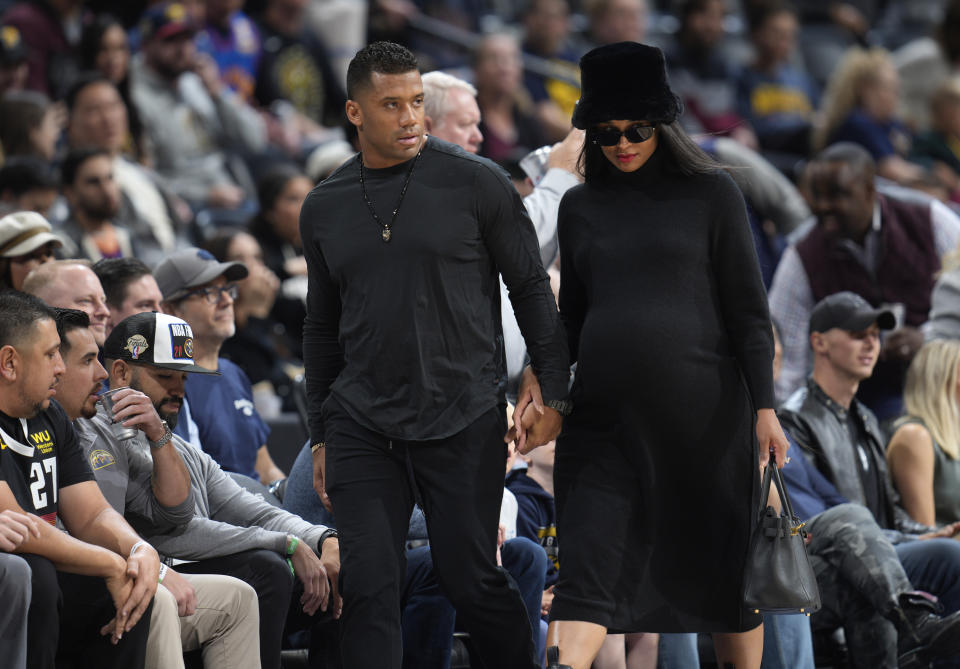 Denver Broncos quarterback Russell Wilson, center left, walks with his wife, center right, rap singer Ciara, to courtside seats to watch the Denver Nuggets host the New Orleans Pelicans in an NBA basketball game on Monday, Nov. 6, 2023, in Denver. (AP Photo/David Zalubowski)