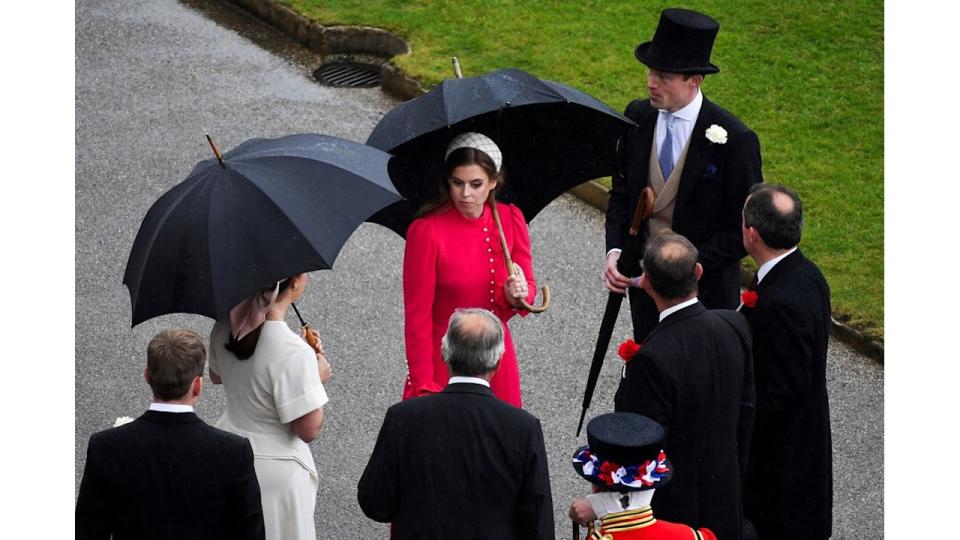 Princess Beatrice wearing red dress and headband at Buckingham Palace Garden Party in the rain