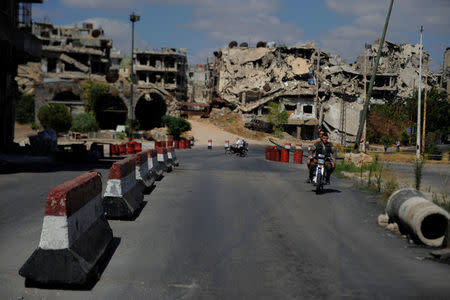 People ride on a motorbike near a Syrian army checkpoint in Homs city, Syria July 29, 2017. Picture taken July 29, 2017. REUTERS/Omar Sanadiki