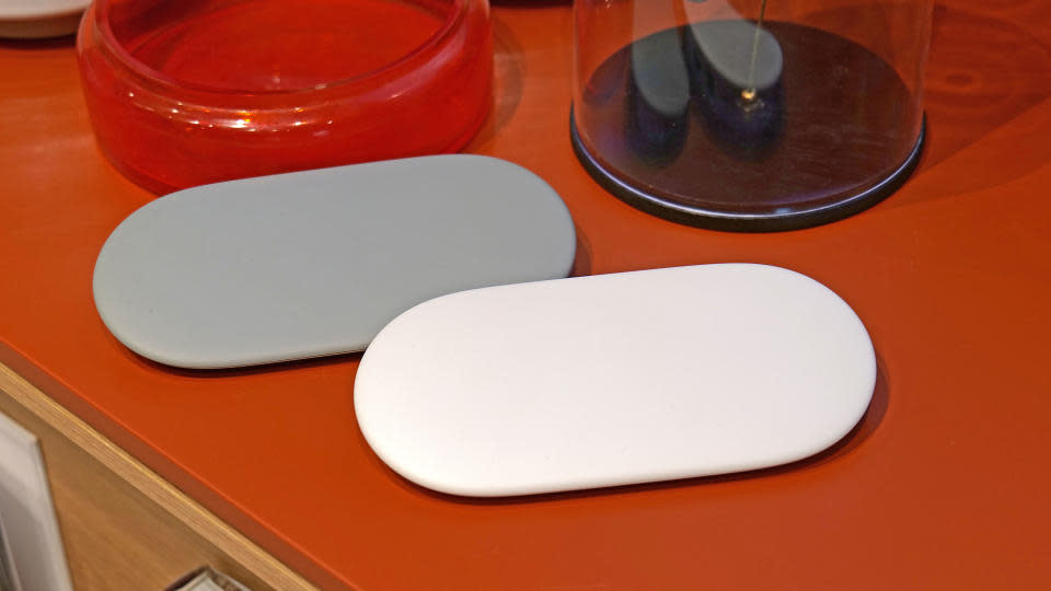 Two Google TV Streamer devices are sitting on the red table.