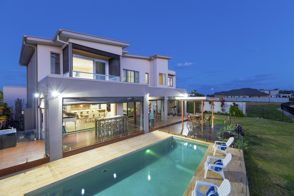 Modern multilevel house exterior with pool at dusk