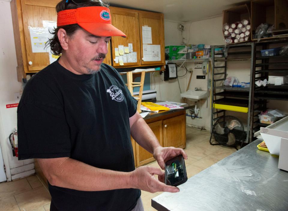 Eric Michener, owner of the Milton Quality Bakery, shows a video from the Sunday night storm that damaged the property as he gives a tour of the temporarily closed shop on Wednesday.