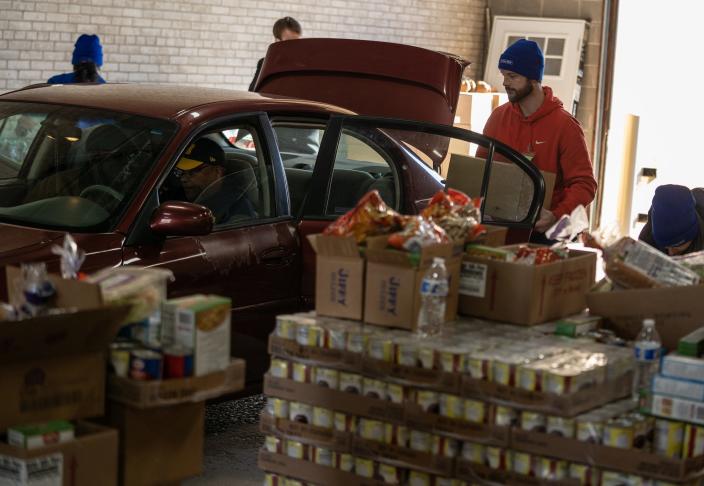Volunteers load a car with food for a traditional Thanksgiving dinner at the Capuchin Soup Kitchen Services Center in Detroit on Tuesday, November 23, 2021.Comerica Bank partnered with Capuchin Soup Kitchen to give 568 families from metro Detroit food to those experiencing hardship. 
