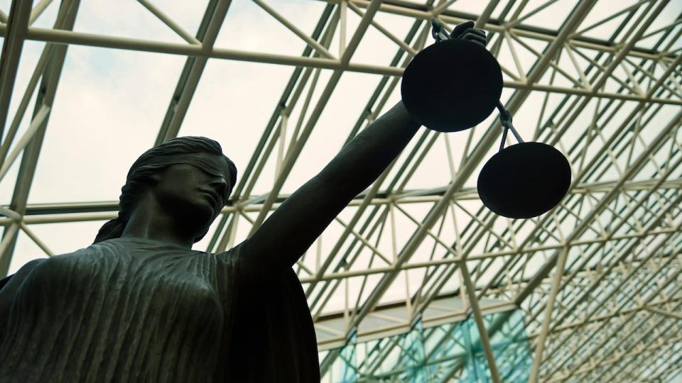 A statue of Lady Justice, blindfolded and holding balanced scales, resides at Vancouver's Supreme Court building. 