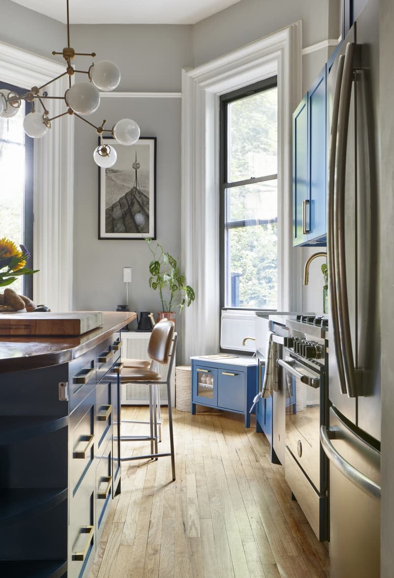 The kitchen is painted gray with blue cabinetry and a multi-arm pendant lamp hanging above the island.