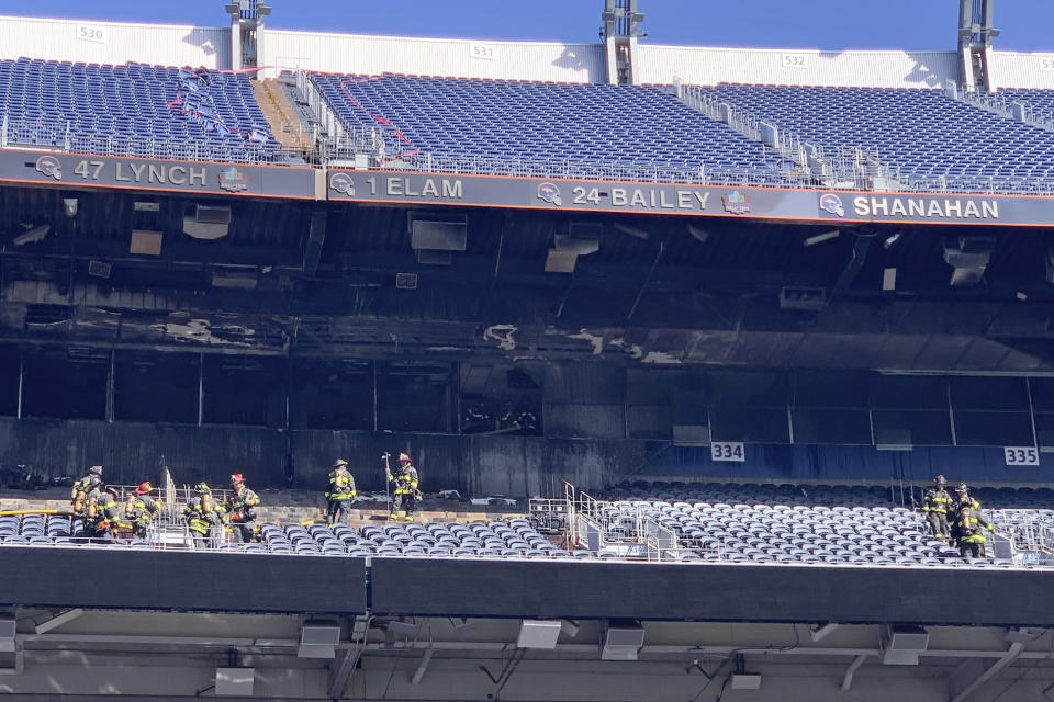 In this photo provided by the Denver Fire Department, firefighters stand watch near a fire-damaged section at Empower Field at Mile High stadium in Denver, Thursday, March 24, 2022. Firefighters have extinguished a blaze that torched several rows of seats and a suite area at the Denver Broncos' stadium. The fire broke out in the third-level and burned at least six rows of seats in two sections. (Denver Fire Department via AP)