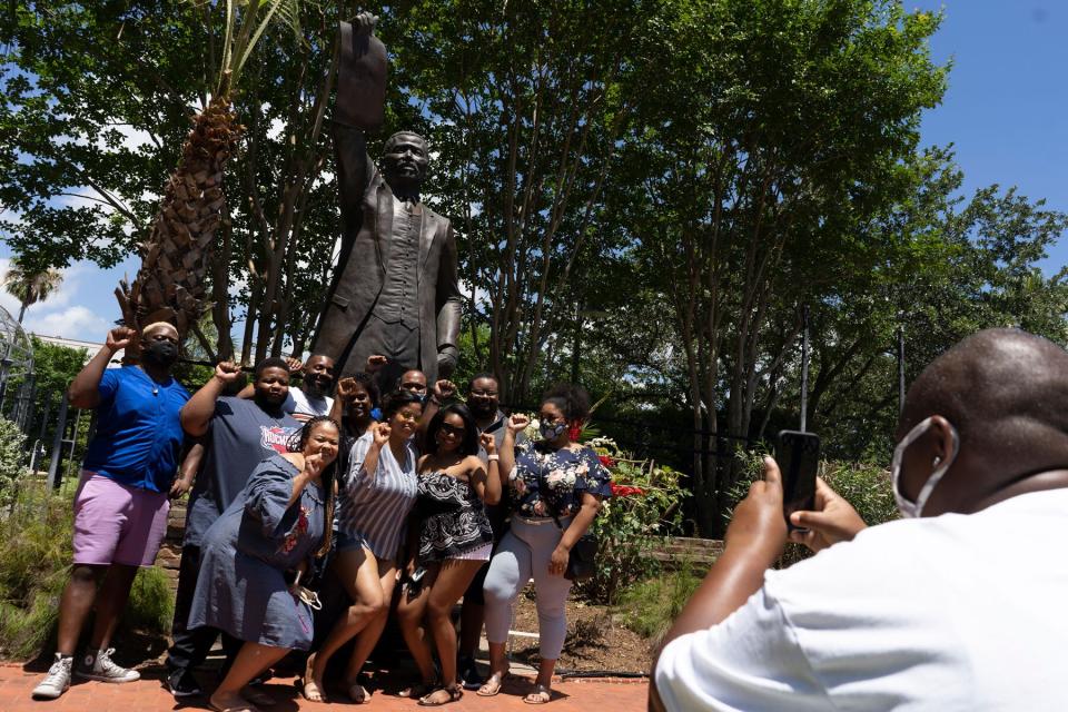 People pose in front of the statue of former Texas Representative Al Edwards