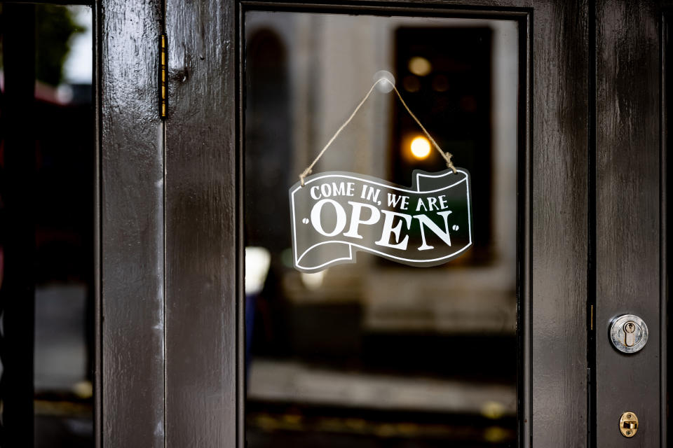 A sign on a glass door reads "Come in! We are OPEN," indicating that a food establishment is open for business