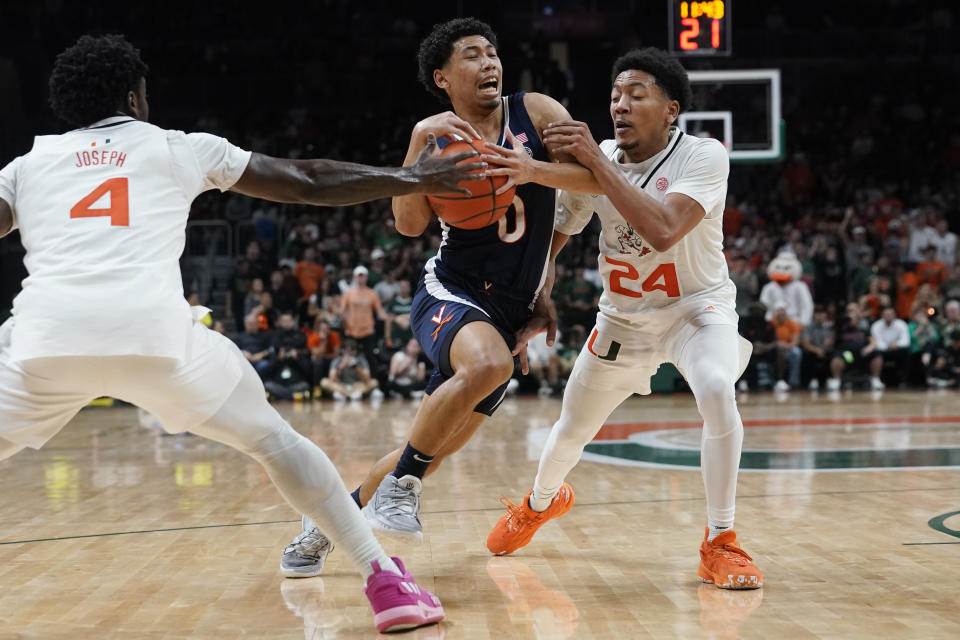 Miami guards Nijel Pack (24) and Bensley Joseph (4) defend Virginia guard Kihei Clark (0) during the second half of an NCAA college basketball game, Tuesday, Dec. 20, 2022, in Coral Gables, Fla. (AP Photo/Marta Lavandier)