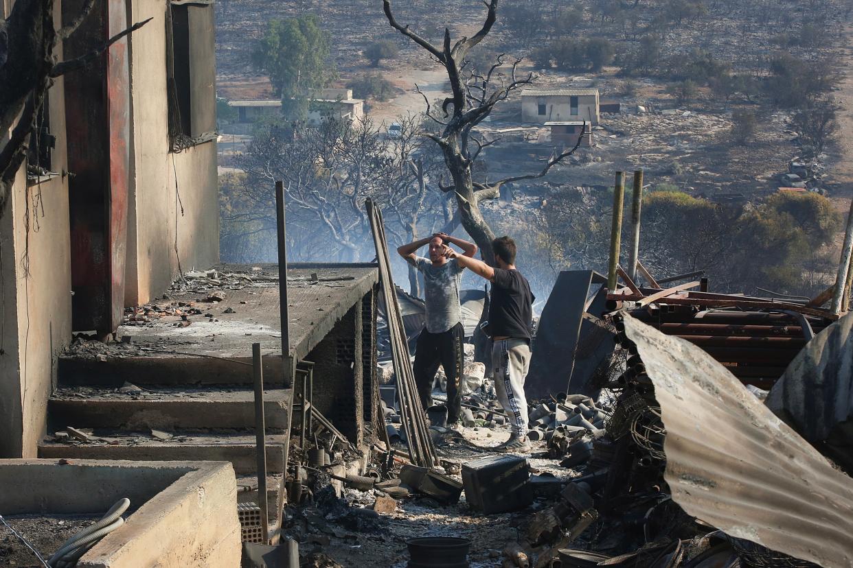 Residents look in despair at their house which has been completely destroyed due to a wildfire, in Dervenochoria, northwest of Attica region, Greece. (EPA)