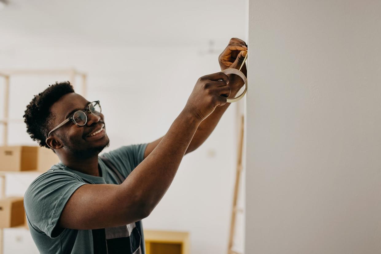 African-American professional painter paints the wall indoors