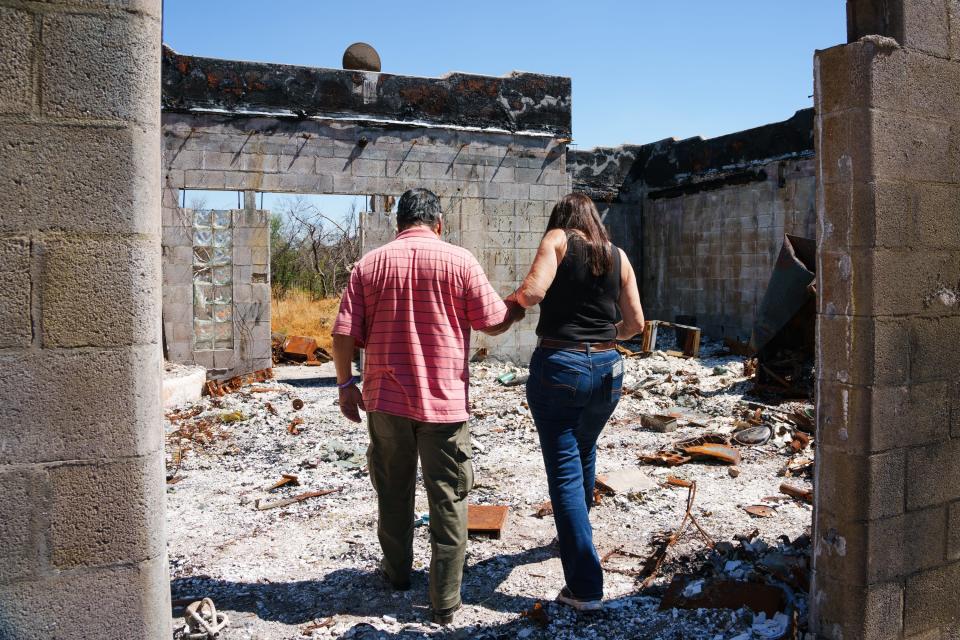 Fernando Villalobos (left) and his caretaker, Sunny Parker, walk through the burned remains of a structure on Villalobos' property on Aug. 5, 2022, in Cave Creek.